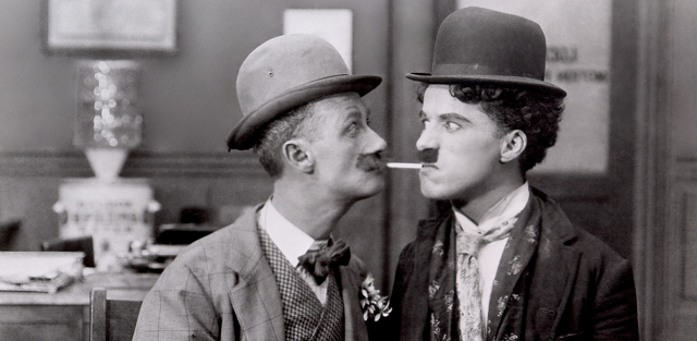 Ben Turpin enoja a Charlie Chaplin en "Charlot cambia de oficio" [1915], sátira de dos rollos de Essanay sobre los hombres de negocios del espectáculo.